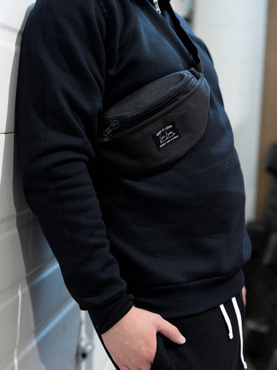 Individual showcasing the black Local Laundry Fanny Pack with the Local Laundry sewn patch on the front of the pack. Made in Canada.