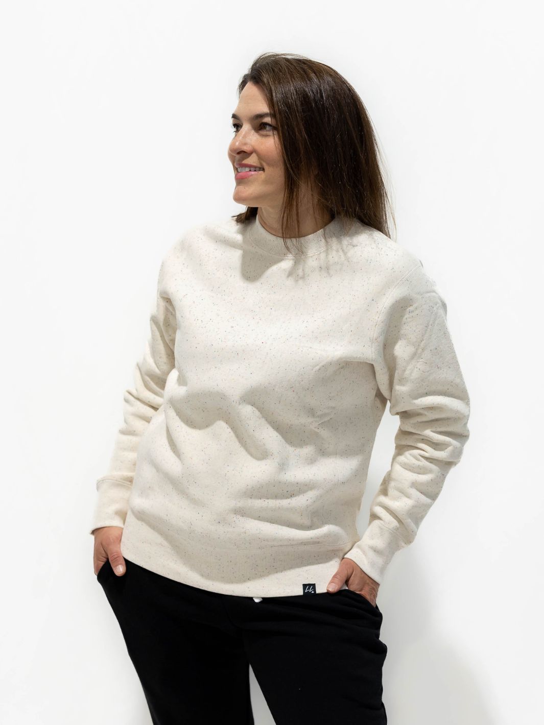 Individual wearing white heavyweight sweater with a multi-colour speckle, featuring the Local Laundry label on the bottom hem. This sweater is made in Canada is constructed using 100% cotton