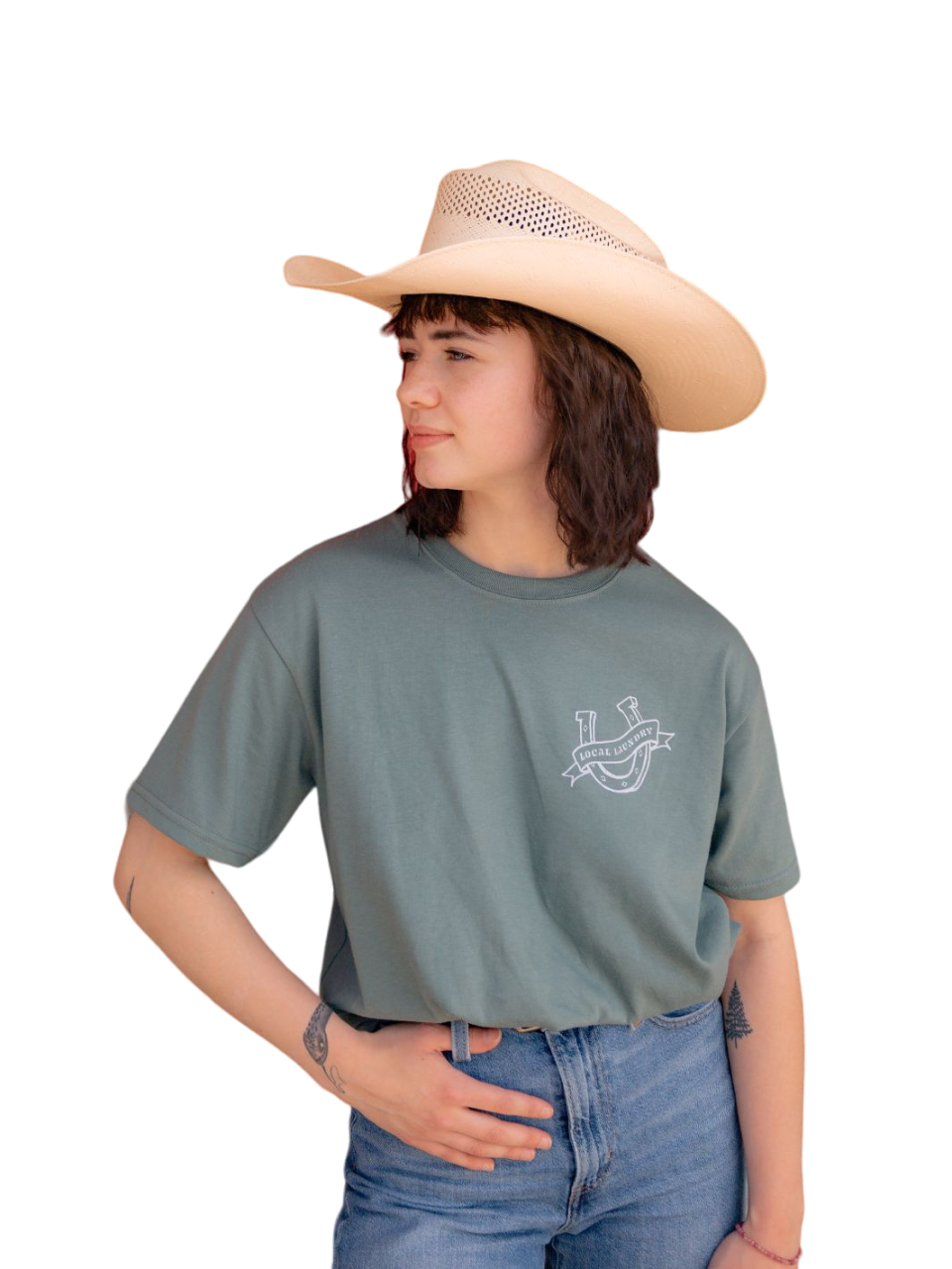 Individual wearing the Saddle Up and Ride shirt in sage green featuring a horseshoe graphic on the left chest with a Local Laundry banner across. Made in Canada, sustainably sourced and made.