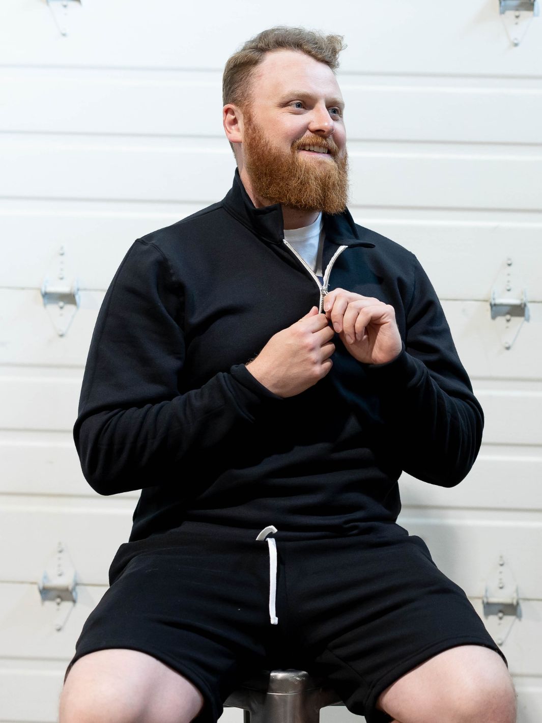 Red haired individual sporting their Made in Canada Local Laundry 3/4 zip Greenview sweater with their Local Laundry Sweat Shorts in black. 