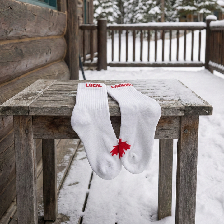 Local Laundry Giving Garment socks with a red maple leaf on a snowy deck
