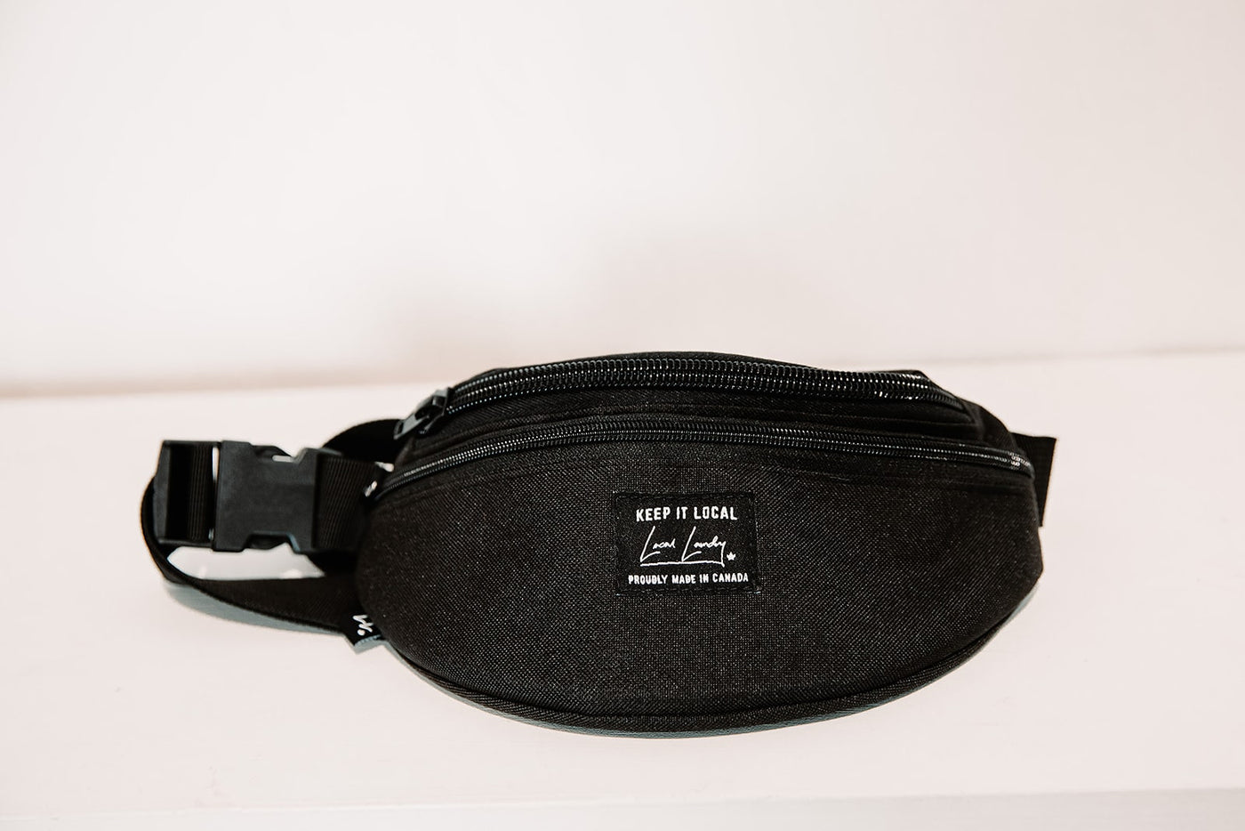 Black Local Laundry Fanny Pack featuring two pockets, made of a polyester outer shell and a nylon interior, with a adjustable Polypropylene strap. Handmade in Canmore Alberta.