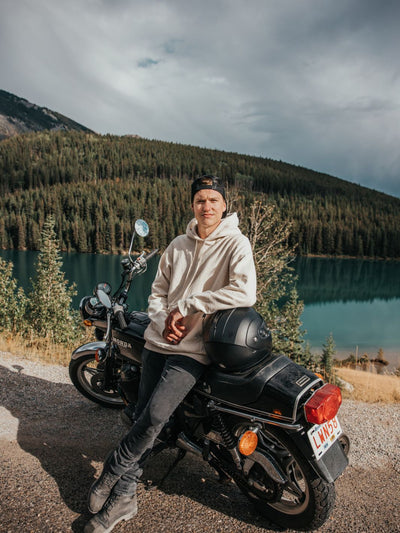 Individual wearing a heavyweight speckled hoodie leaning against their motorbike in the mountains. This 100% cotton heavywieght hoodie is ideal for those colder temperatures. Sustainably made in Canada 