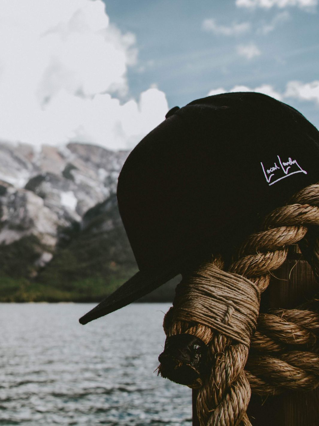 Local Laundry Rundle Snapback hat in black resting atop a bundle of rope in the mountains. This hat is made in Vancouver, Canada.