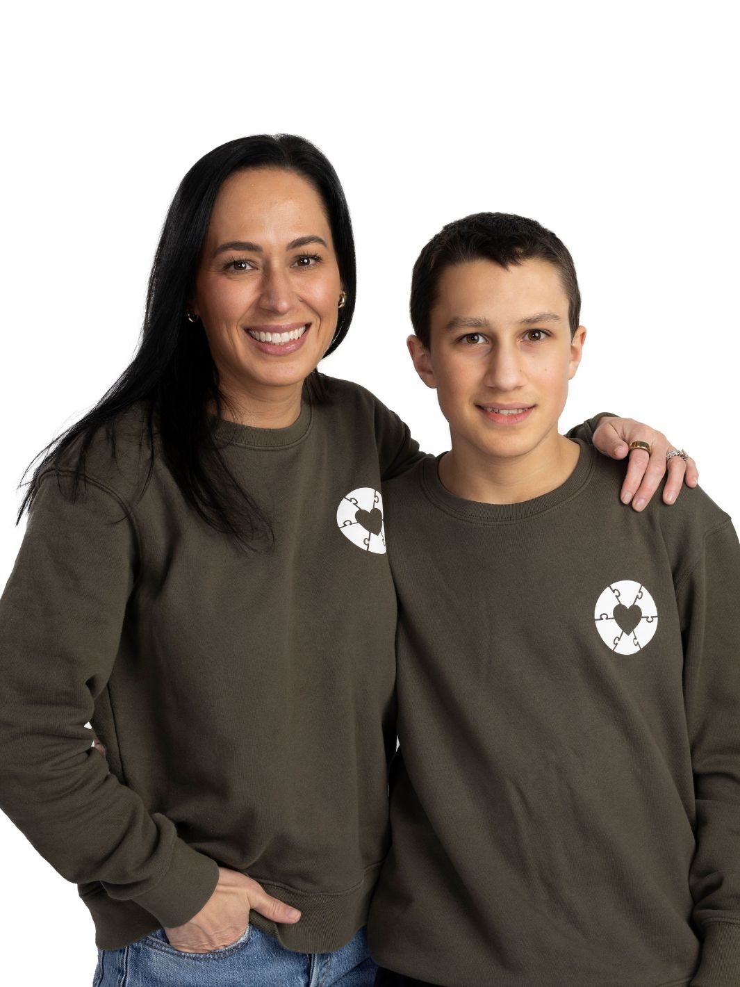 Two individuals wearing olive green sweaters that feature the Ryder's Foundation heart logo on the left chest. Made in Canada, upholds sustainable fashion while supporting local communities.