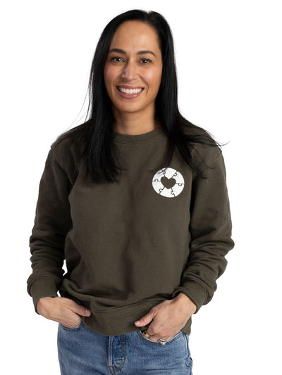 Individual wearing Canadian made sweater in olive green featuring a white heart design on the left chest. This Local Laundry sweater is made of ethically sourced 100% cotton and is cut and sewn in Canada.