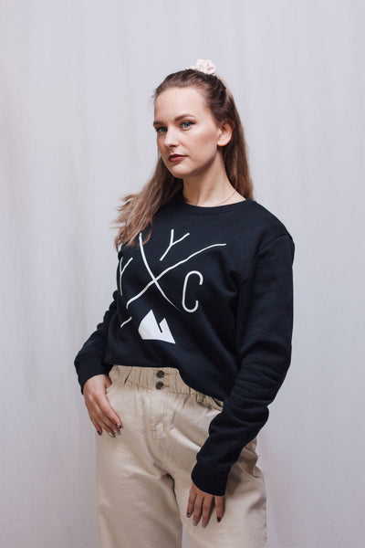 Individual wearing the Local Laundry YYC Crewneck sweater in black. This sweater features the Local Laundry trademarked YYC graphic that represents the bring together of local communities through sustainable and local garments.